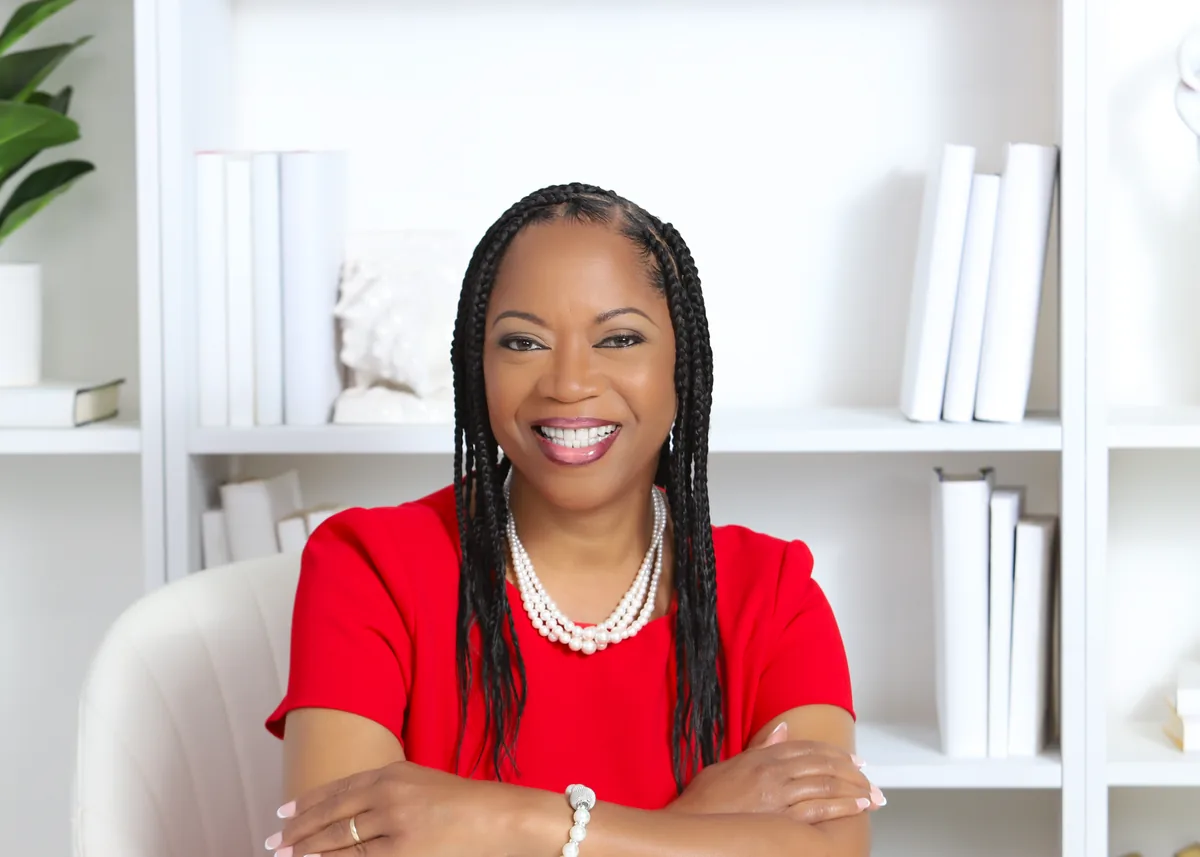 Dinah Rainey at her desk in a red top, smiling.
